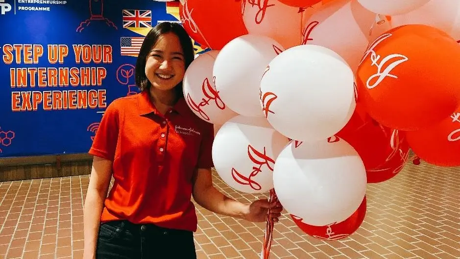 A woman holds balloons while smiling at an event showcasing IMDA's efforts to nurture Singapore's tech talent for the digital future