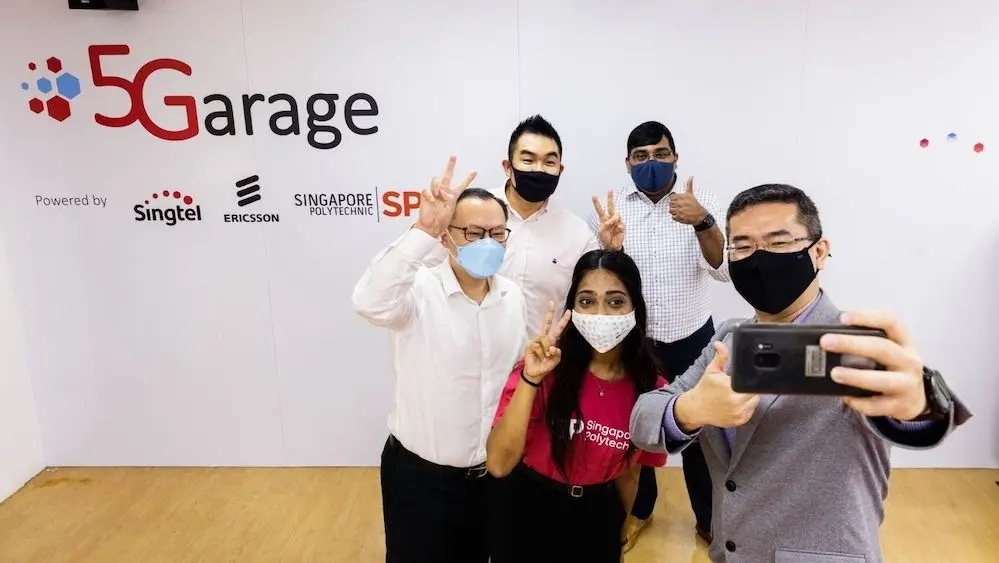 A group of professionals working on Singapore's 5G future, taking a group photo as part of the trials and programs supported by IMDA