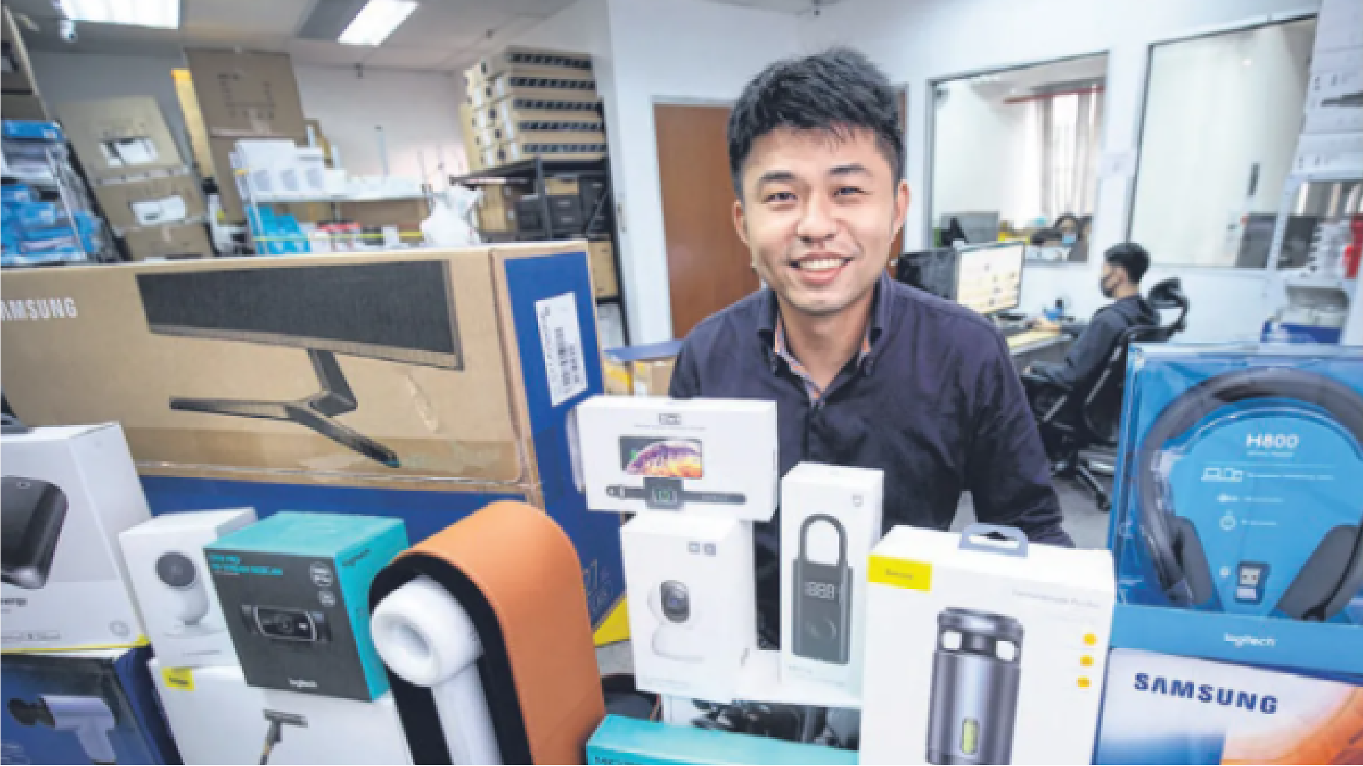 A man smiling, surrounded by electronics at his desk, highlighting Kearea's use case for data-driven business through the BDDB programme