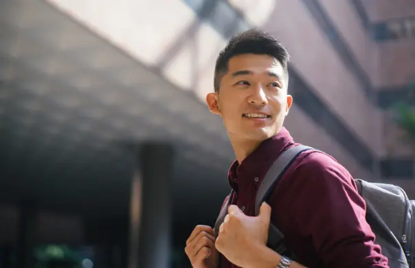 Asian male carrying a backpack and smiling