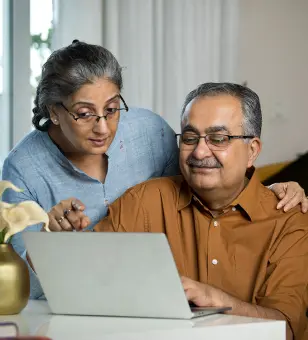 An elderly couple takes part in IMDA's digital literacy programme as they use a laptop at home, smiling as they navigate the Internet