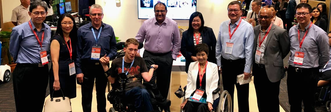Participants posing with Mr S Iswaran at the E2Connect 2018 exhibition, featuring a range of assistive tech tools