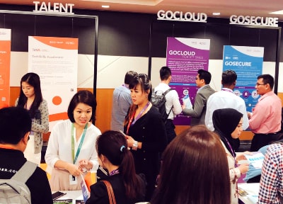 Participants interacting on the exhibition floor at IMDA's SG:D Industry Day, discussing various digital solutions and IMDA programmes