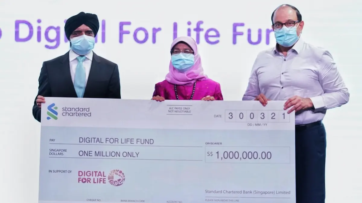Digital for Life movement: President Halimah Yacob holding a $1 million cheque with two other representatives from Standard Charted Bank