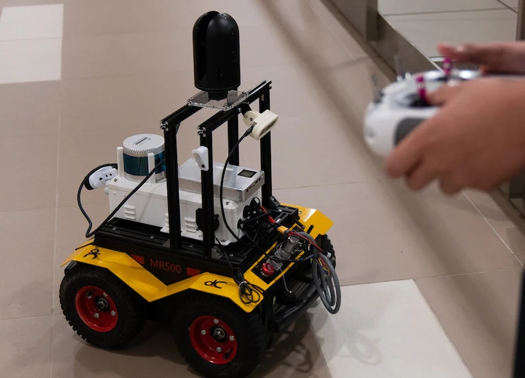 A yellow Simultaneous Localisation and Mapping (SLAM) robot in a corridor being controlled by a white handheld console.