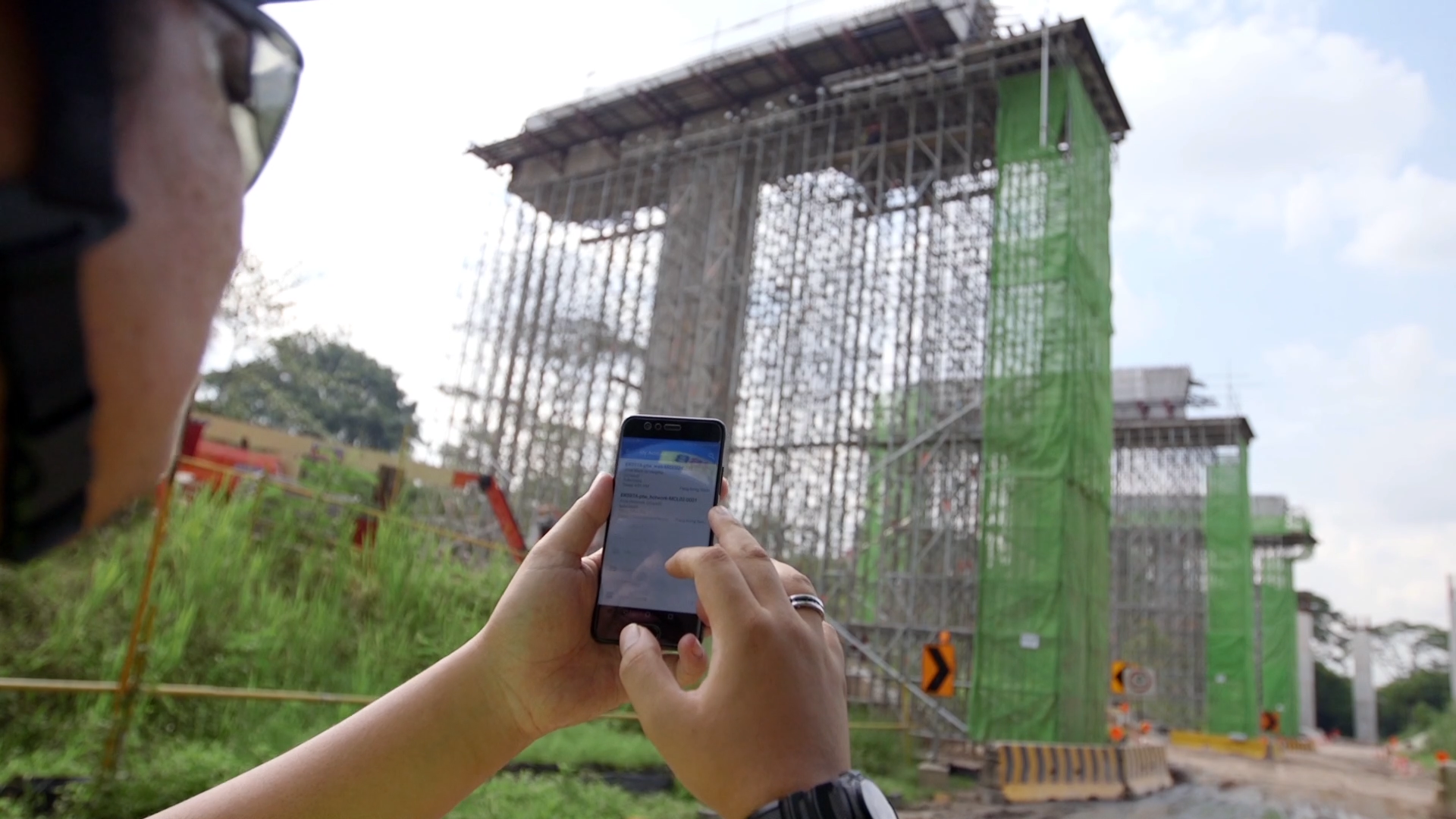 Woman on a construction site using Novade's Safety-HSE module on her phone, showcasing HSB's IMDA-accredited focus on safety standards