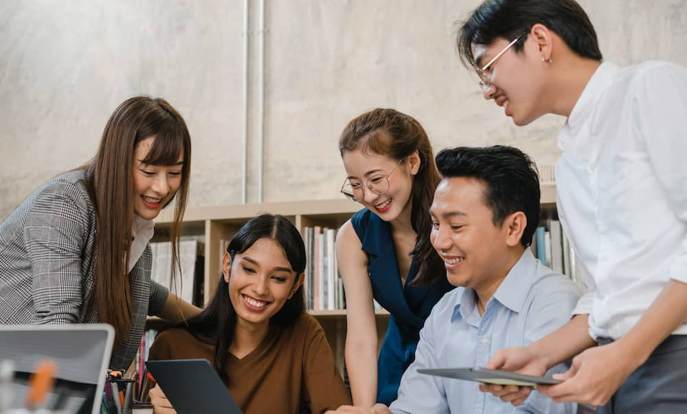 Office workers gathered around a laptop