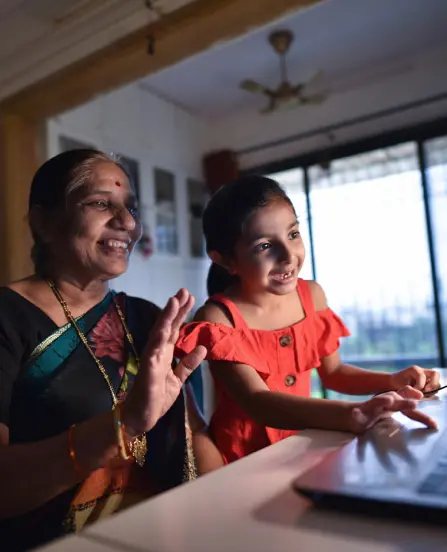 IMDA's seniors go digital programme: a young girl teaches her grandmother how to use the laptop at home for digital literacy and wellbeing
