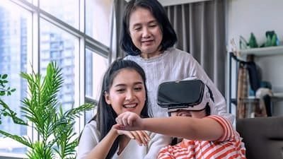 Multi-generation family in a living room with daughter wearing virtual reality (VR) goggles
