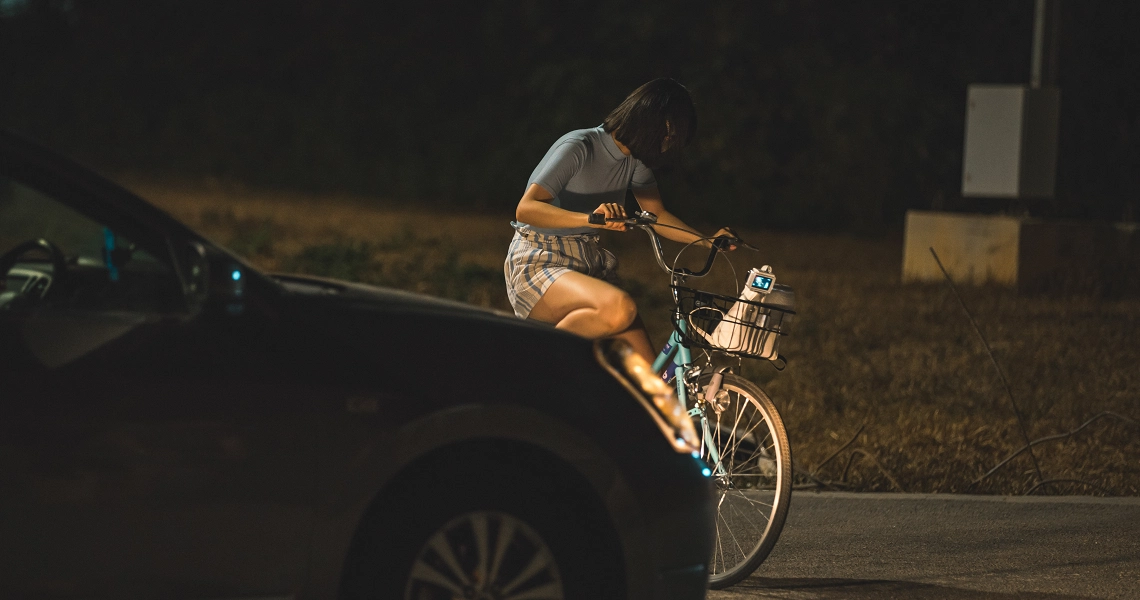 A cyclist performs a daring jump over a car at night in a scene from the film "Late Night Ride".