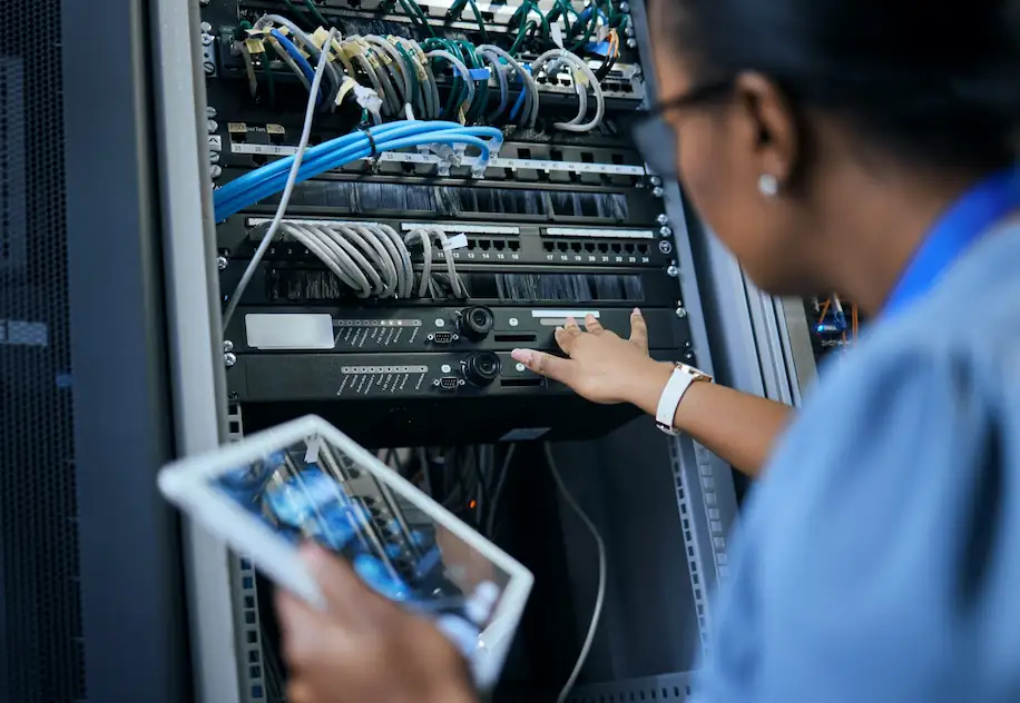 Lady holding a tablet while checking a data server. 