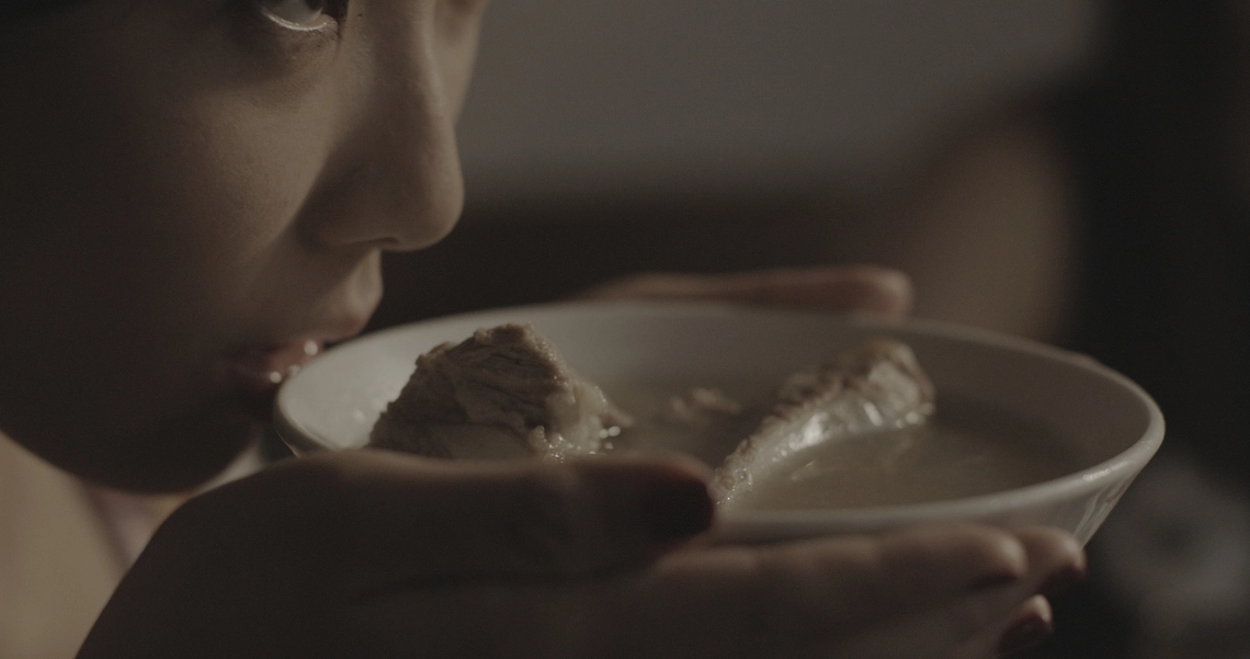 A film still from Lang Tong shows a person holding a plate with fish, capturing a tense moment in the Singaporean thriller.