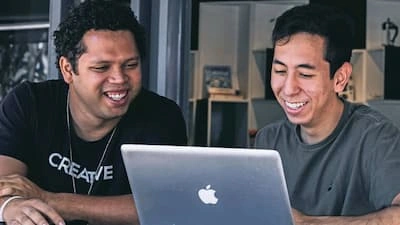 Two young men working together on a laptop. Singapore's robust digital connectivity infrastructure provides individuals with the opportunity to benefit from the digital economy. 